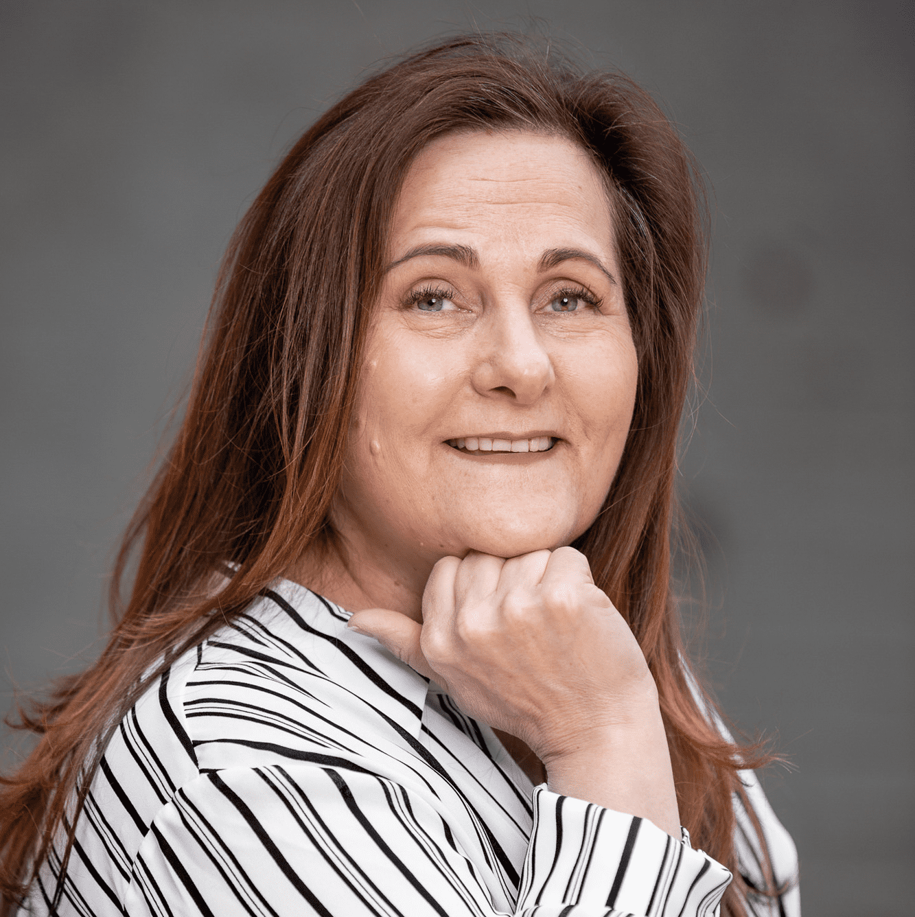 Professional photo of Susan Licata wearing a white and black striped dress shirt and smiling at the camera.