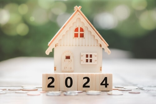 Photo of a house made of wood with a blurry background effect and blocks in front that show the year 2024.